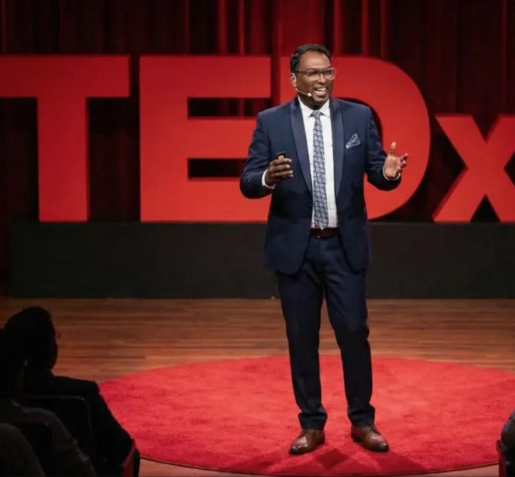 Joel Dave speaking on the TEDx stage.